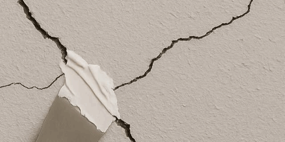 Repairing drywall crack with putty knife and wall filler